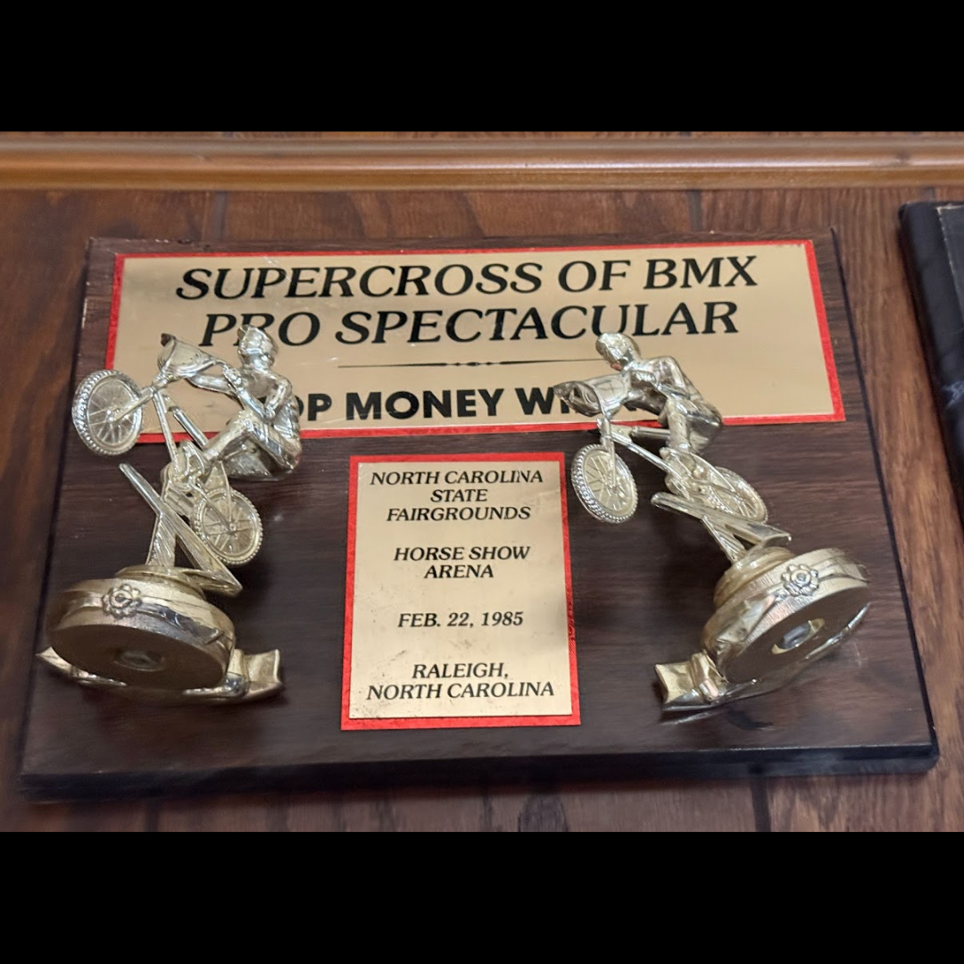 Wooden Supercross of BMX Pro Spectacular Top Money Winner plaque with two silver BMX rider figures, dated February 22, 1985.