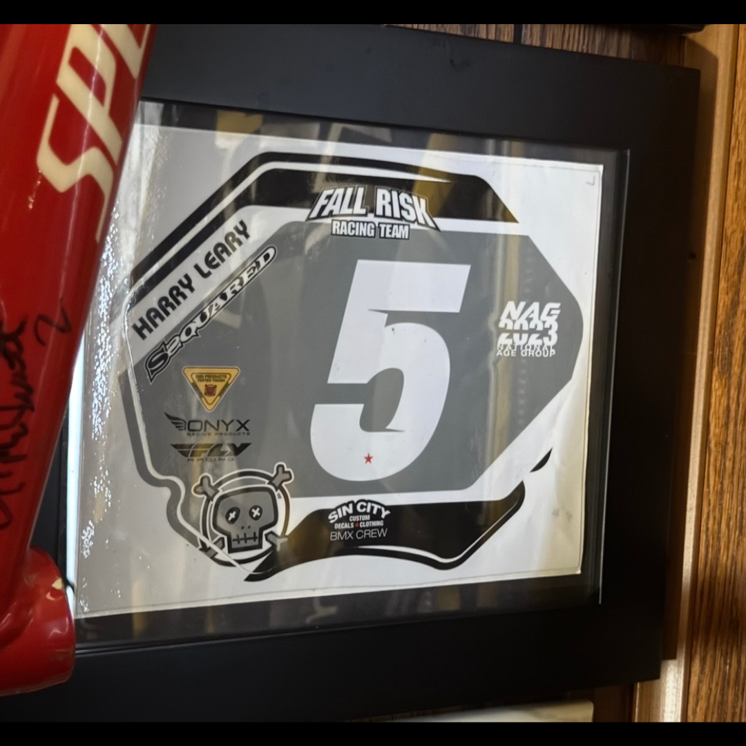 Framed black, white and gray Fall Risk Racing number-plate decal marked Harry Leary and number five.