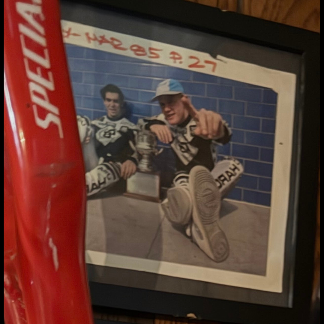 Framed vintage photograph of two BMX riders seated together with a trophy, identified as Harry Leary and Eddy King.