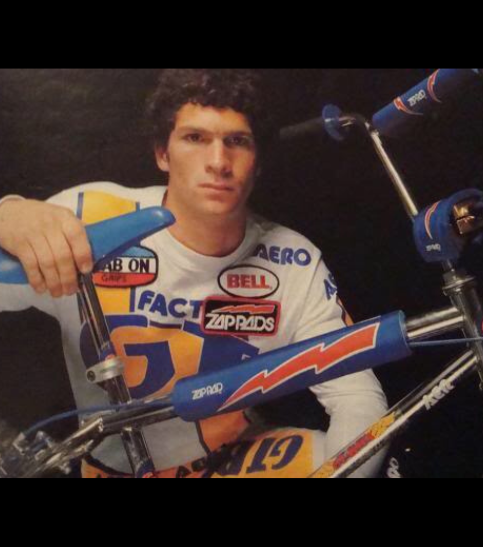 Greg Hill posed with a BMX bike in race gear in a vintage portrait image