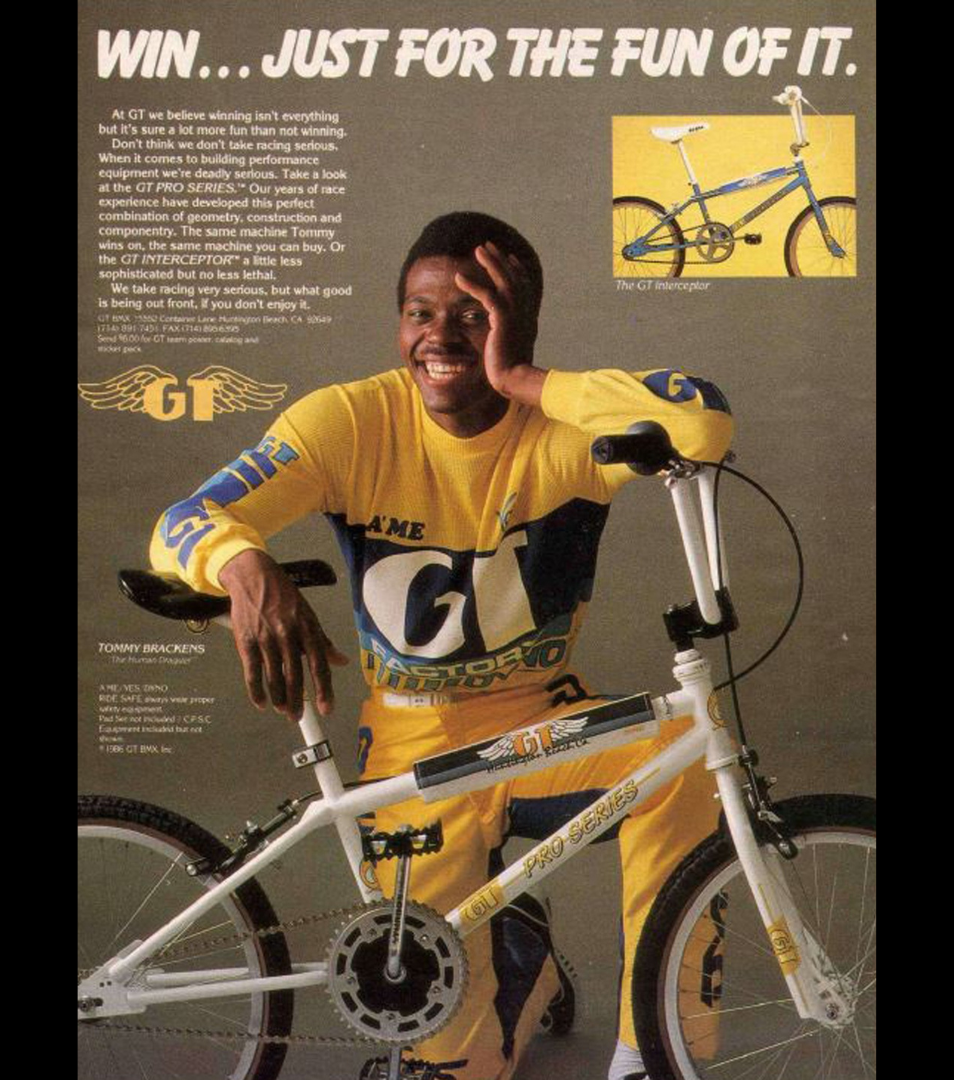 Tommy Brackens in yellow and blue GT racing gear posing beside a white GT Pro Series BMX bike in a vintage advertisement